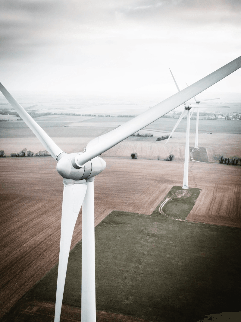 Desaturated aerial photo of white wind turbines over farm fields