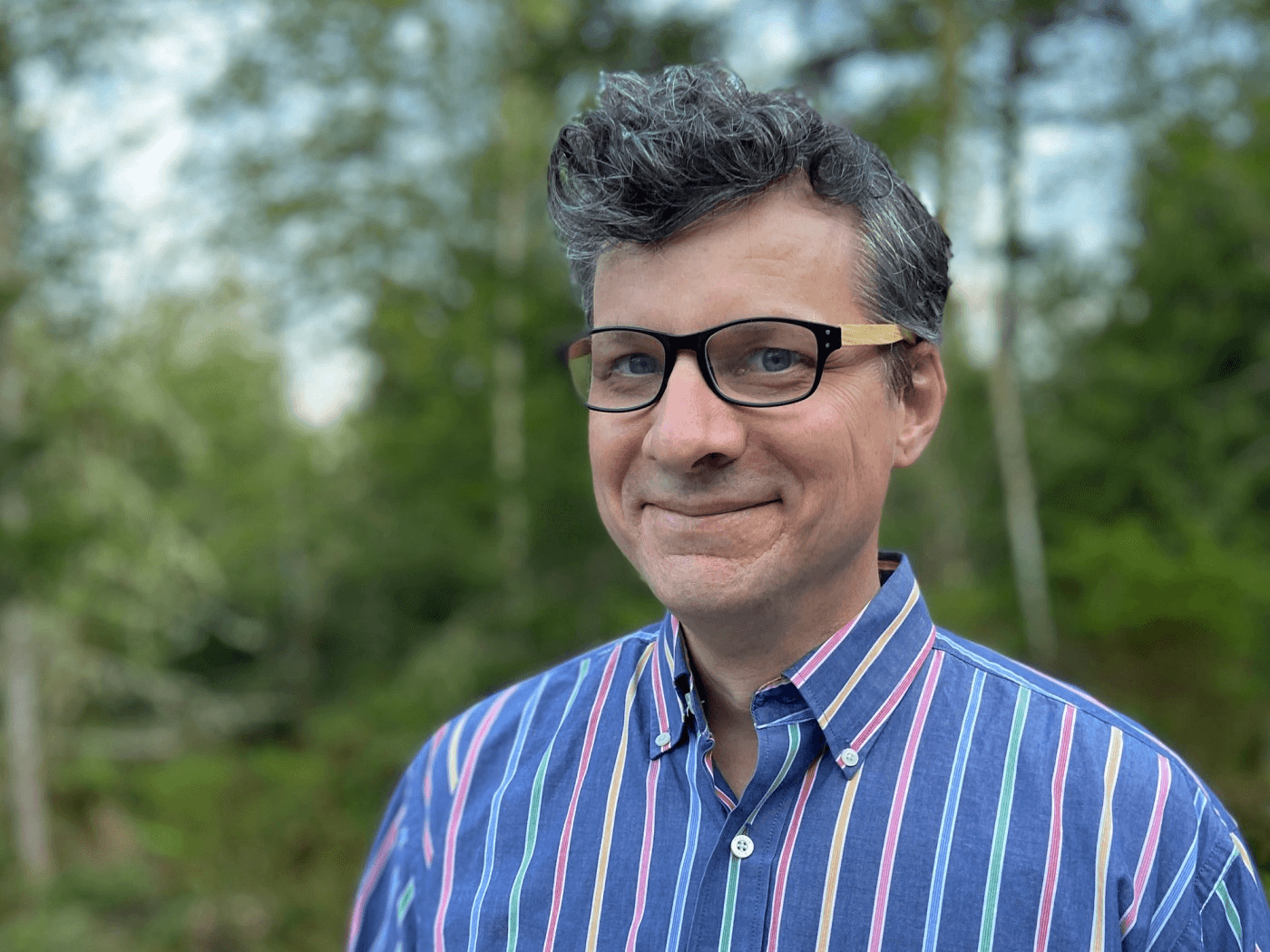 Portrait of a middle aged man smiling in a bemused way in the forest